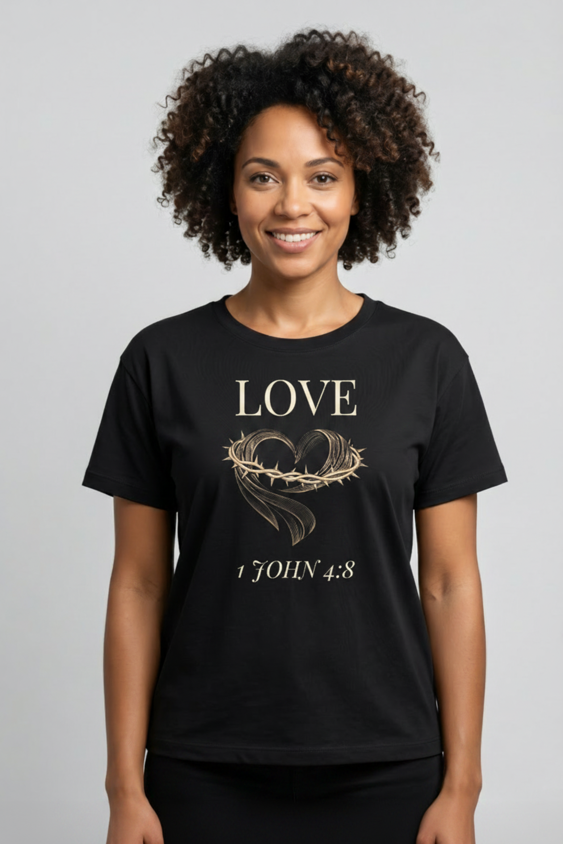 Smiling woman wearing black Fruit of the Spirit Love t-shirt featuring crown of thorns heart design and 1 John 4:8 KJV verse, part of the Jamaican Christian apparel collection by Island Print Impression
